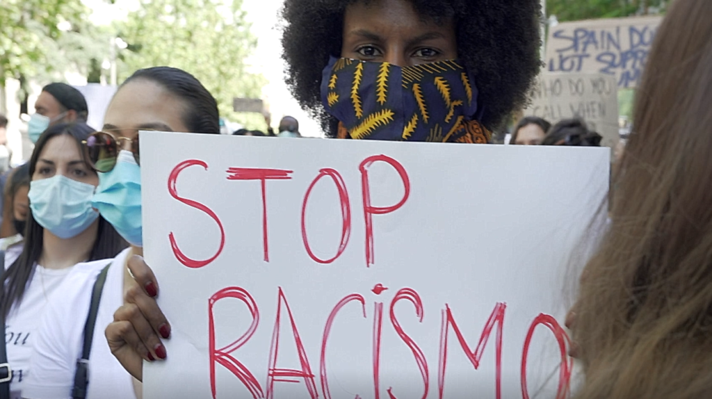 Una mujer de color con la pancarta Stop Racismo