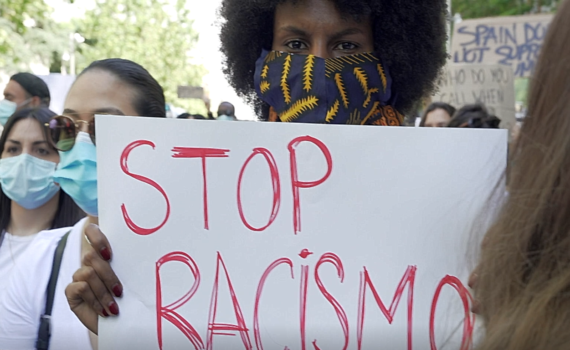 Una mujer de color con la pancarta Stop Racismo