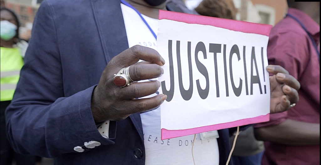 Una mujer sostiene una pancarta con la palabra Justicia
